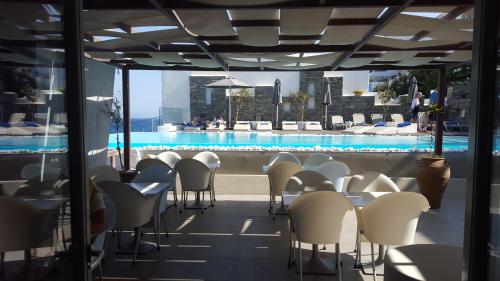 a balcony with tables and chairs and a swimming pool at Hotel Senia - Onar Hotels Collection in Naousa