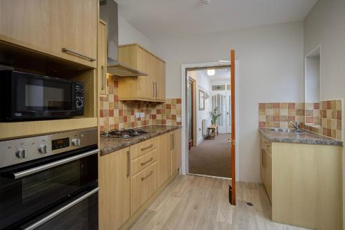 a kitchen with wooden cabinets and a stove top oven at Arnside - Spacious 10-Bedroom Seaside Cottage in Blackpool