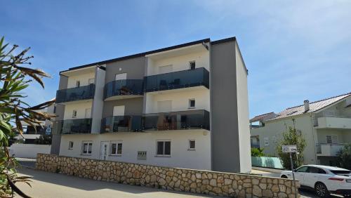 ein Gebäude mit Balkonen an der Seite in der Unterkunft THREE FLOOR Deluxe Pool Apartments in Novalja