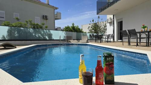 ein Pool mit zwei Flaschen Getränken daneben in der Unterkunft THREE FLOOR Deluxe Pool Apartments in Novalja