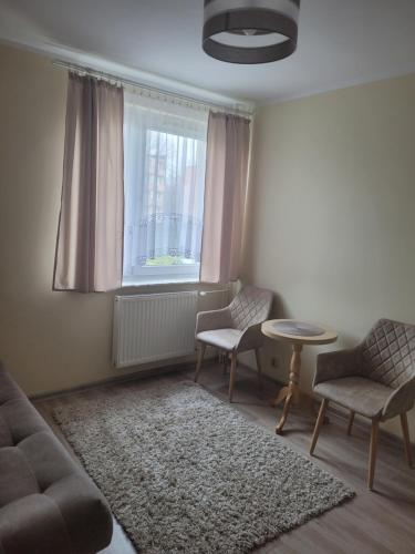 een woonkamer met een bank en stoelen en een raam bij Przystanek Hel in Hel
