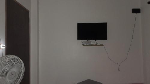 TV de pantalla plana colgada en una pared con ventilador en บ้านพัก en Ban Bang Pho