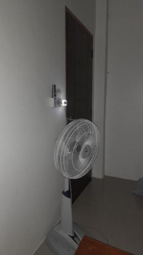 un ventilador blanco sentado en una esquina de una habitación en บ้านพัก en Ban Bang Pho