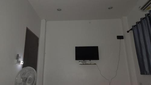 telewizor z płaskim ekranem na białej ścianie w pokoju w obiekcie บ้านพัก w mieście Ban Bang Pho