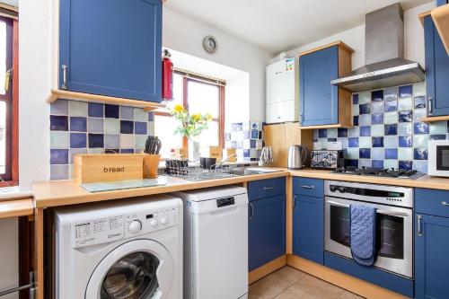 a kitchen with blue cabinets and a washer and dryer at Ferienhaus für 4 Personen ca 53 qm in Saint Columb Major, England Westküste von England in Saint Columb Major