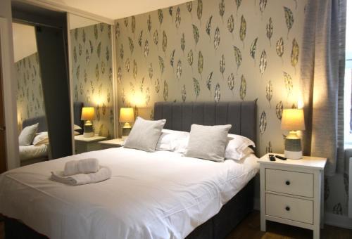 Schlafzimmer mit einem weißen Bett und einem Spiegel in der Unterkunft Corbiere House @ Short Stays in Basingstoke