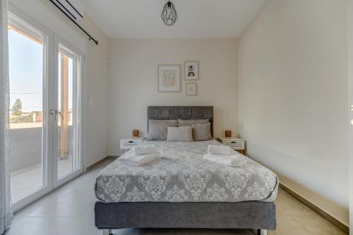 a bedroom with a bed and a large window at Newly Built Home with Garden, 400m to Beach in Kokkíni Khánion