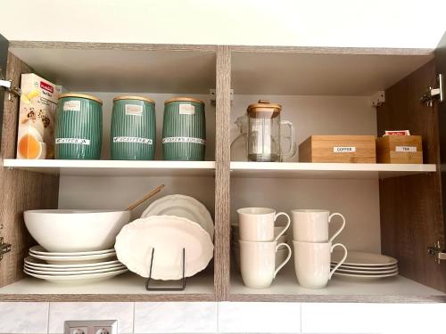 a cupboard with plates and bowls and other dishes at Großes Apartment mit Terrasse und Garten in Oberhaching