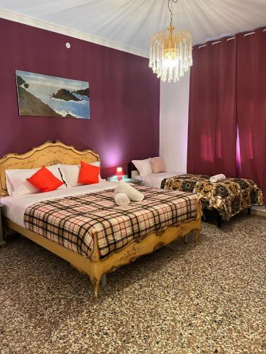 two beds in a room with purple walls and a chandelier at S Marco Apartments - Urban Boutique & Venice Link in Mestre