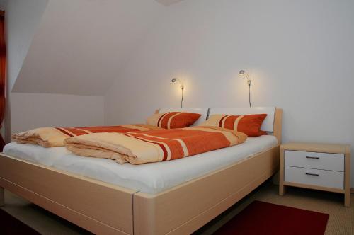 MunningenにあるGabis-ferienwohnungのベッドルーム1室(オレンジ色の枕が付いたベッド1台付)
