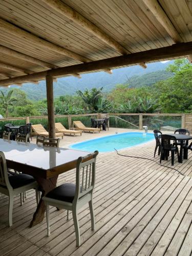 eine Terrasse mit einem Tisch und Stühlen sowie einem Pool in der Unterkunft Recanto Águas do Quiriri in Garuva