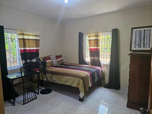 a small bedroom with a bed and two windows at The Kozy Kotch in Montego Bay