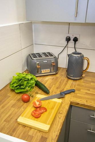 a cutting board with a knife and some vegetables on a counter at CADeS accommodation in Wolverhampton