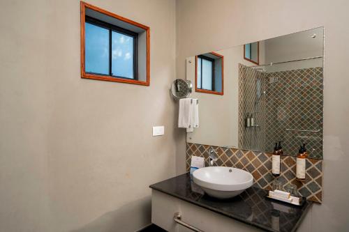 een badkamer met een wastafel en een spiegel bij The Hive, Wayanad in Wayanad