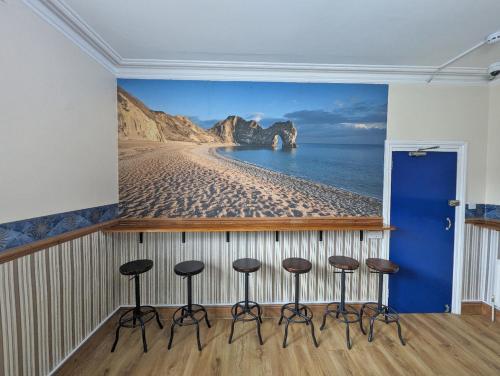 een kamer met een muurschildering van een strand en krukken bij Jurassic Bay Holidays in Weymouth