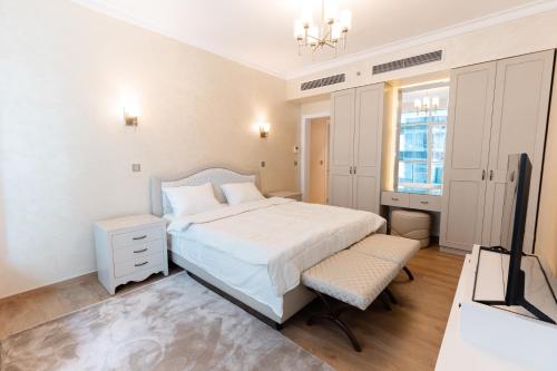 a white bedroom with a bed and a television at Studio Apartment - Maadi in Cairo