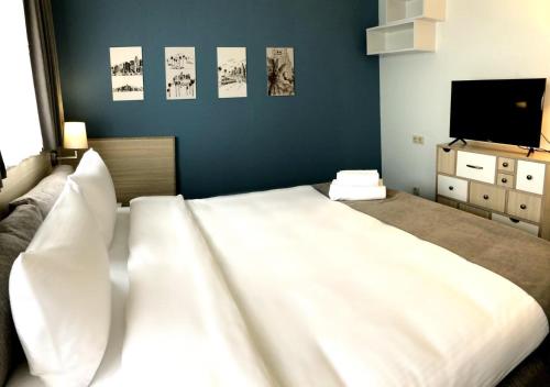 Schlafzimmer mit einem großen weißen Bett und einem Flachbild-TV in der Unterkunft Hotel In City in Yerevan