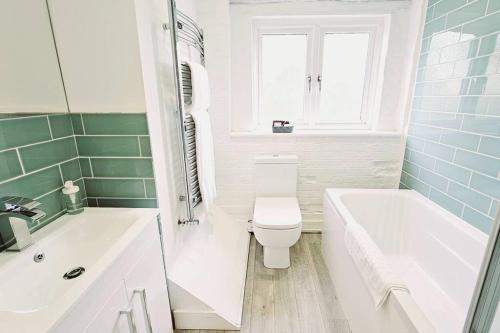 a bathroom with a toilet and a tub and a sink at Oakdale at Weavers Yard No2 in Farnham