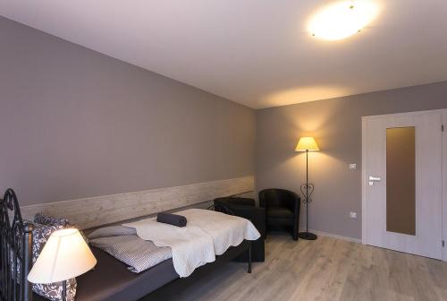 a bedroom with a bed and a chair and a lamp at Penzion Na Palubě in Jeseník