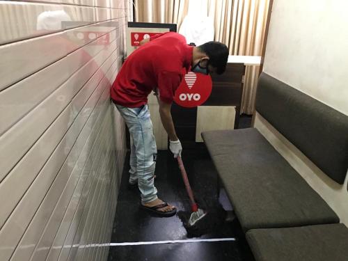 Un hombre está limpiando el suelo en un vestuario. en OYO Chaithanya Complex en Muttam