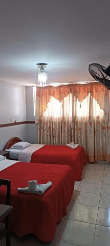 two beds with red sheets in a room at HOTEL LAS GARDENIAS in Trujillo