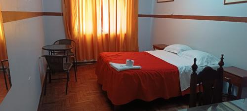 1 dormitorio con 1 cama con manta roja en HOTEL LAS GARDENIAS, en Trujillo