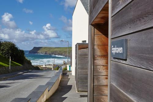 a sign on the side of a building next to the ocean at Epphaven in Polzeath