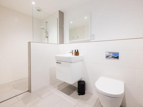 a white bathroom with a toilet and a sink at Epphaven in Polzeath