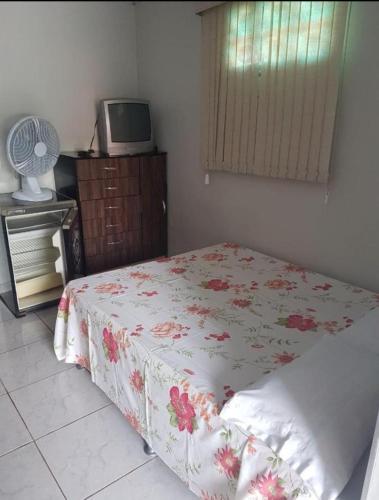 a bedroom with a bed with a flowered blanket and a tv at Pousada Econômica in Uberlândia