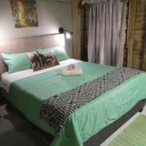 a bedroom with a large bed with a green blanket at Shangrila-innibos Country Lodge in Hartbeespoort