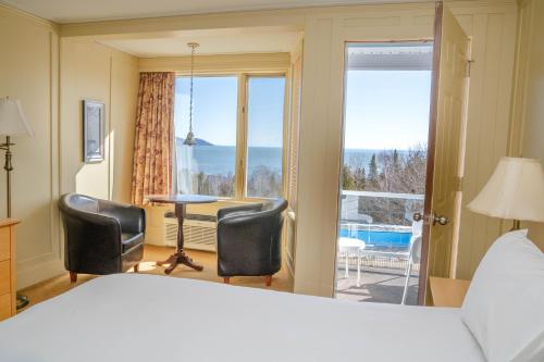 a bedroom with a bed and two chairs and a window at Auberge Des 3 Canards in La Malbaie