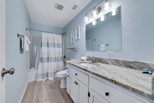 ein Badezimmer mit Waschbecken, Toilette und Spiegel in der Unterkunft Beach Energy in Gulf Shores