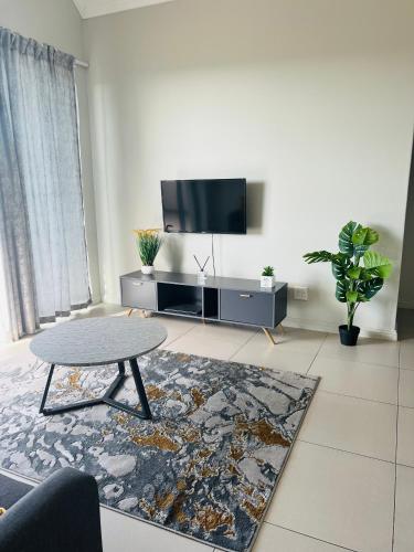 uma sala de estar com uma mesa e uma televisão de ecrã plano em Carlswald Apartments em Midrand
