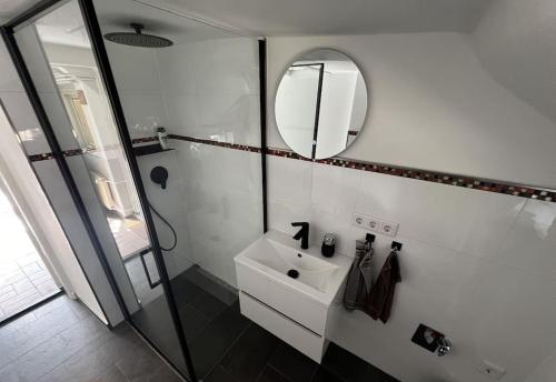 a white bathroom with a sink and a mirror at Cottage mit Garten in Michendorf