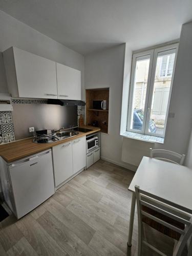 une cuisine avec des armoires blanches, une table et une fenêtre dans l'établissement Au deux enfants, à Angoulême