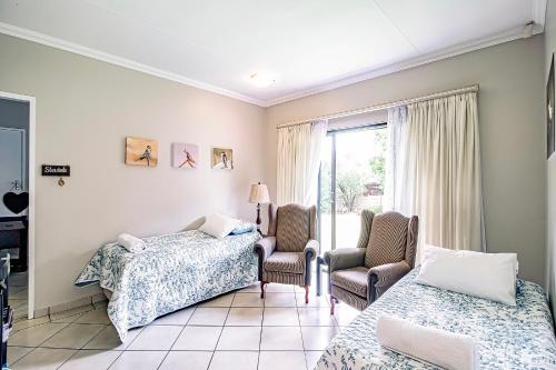 Habitación con 2 camas, 2 sillas y ventana en LeoZet Self catering apartment en Pretoria