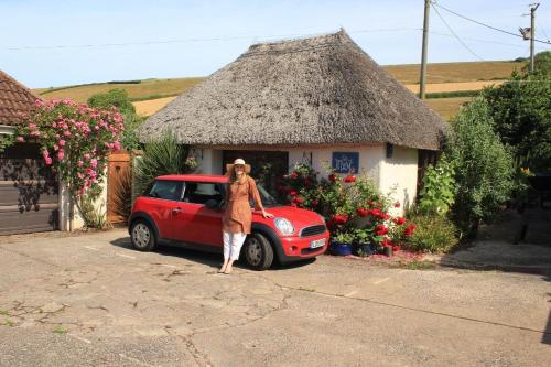 una mujer parada frente a un pequeño coche rojo en Ferienhaus für 2 Personen ca 50 qm in Stokeinteignhead, England Südküste von England en Stokeinteignhead