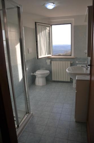 een badkamer met een toilet, een wastafel en een raam bij Poggio dei Venti in Monterotondo