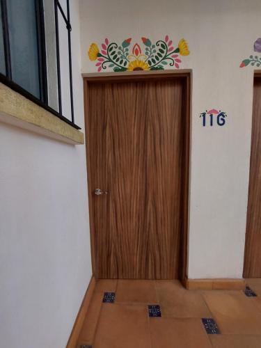 uma porta de madeira num quarto com uma flor na parede em POSADA GUADALUPE Habitación sencilla #116 em Aguascalientes