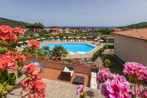 vista sulla piscina di un resort con fiori di Hotel Residence Isola Verde a Marciana Marina