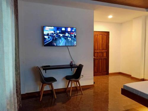 Pokój z 2 krzesłami i biurkiem z telewizorem na ścianie w obiekcie GBU Loboc River Guesthouse w mieście Loboc
