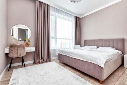 a bedroom with a bed and a mirror and a chair at 2-х комнатная возле ЭКСПО in Astana