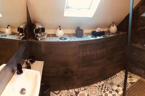 La salle de bains est pourvue d'un lavabo et d'une baignoire avec vases. dans l'établissement Gîte les filous Maison avec piscine et dépendance, à Avallon