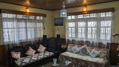 a living room with two couches and two windows at Homestay Darjeeling in Darjeeling