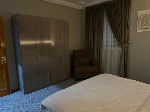 a bedroom with a bed and a chair and a cabinet at الجوار in Al Madinah