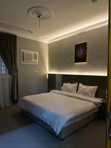 a bedroom with a bed with white sheets and pillows at الجوار in Al Madinah