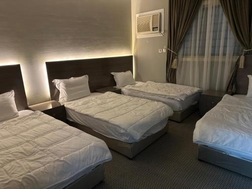 a hotel room with three beds in a room at الجوار in Al Madinah