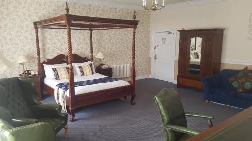 a bedroom with a canopy bed and two chairs at Haughton Hall in Telford