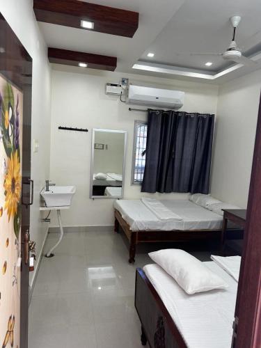 a room with two beds and a sink and a mirror at Temple View Home Stay in Tiruvannāmalai