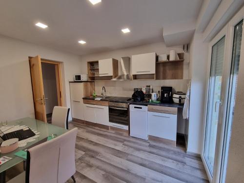a kitchen with white cabinets and a table with a dining room at Apartments Jasko in Ig